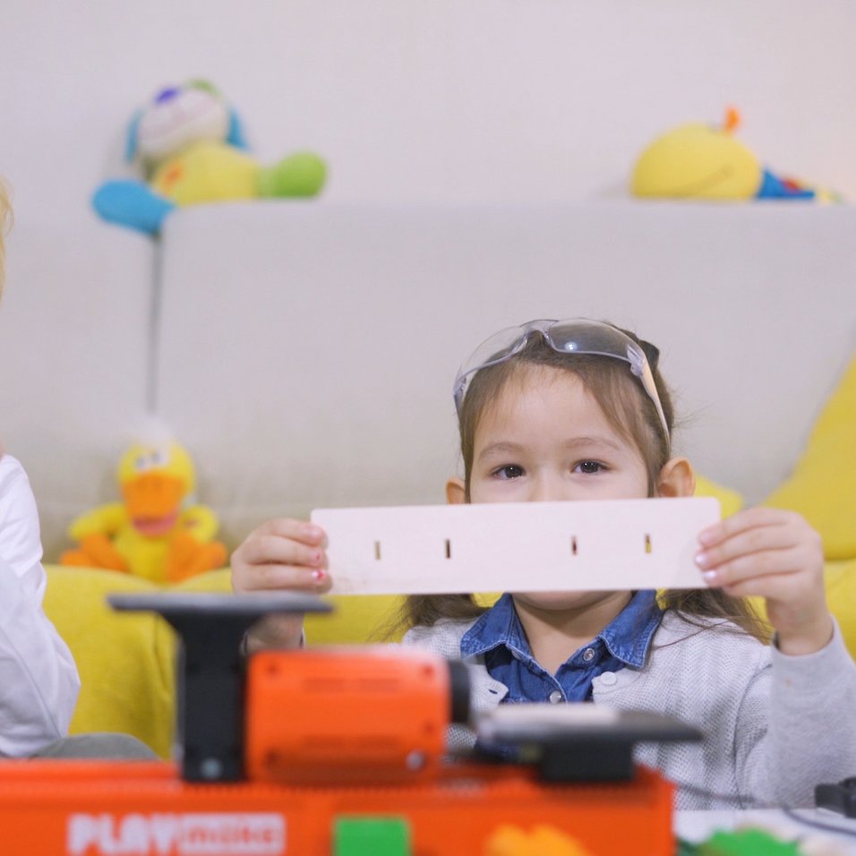 two children showing projects made with playmake